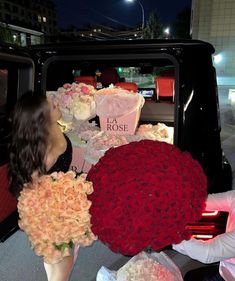 two women are sitting in the back of a truck with roses on it and boxes full of flowers