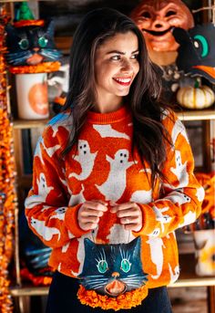 a woman wearing an orange and white sweater with a cat on it's chest