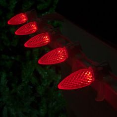 four red lights are on the side of a building in the dark with trees behind them