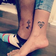 two people with matching tattoos on their feet, one has a key and the other has a heart