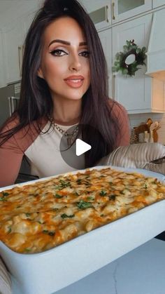 a woman is holding up a large casserole dish