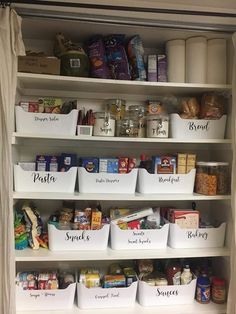 an organized pantry with white bins filled with food and labeled labels on the shelves