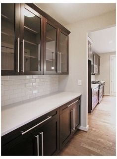 a kitchen with dark wood cabinets and white counter tops, along with hardwood flooring