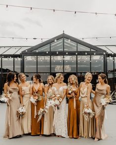 a group of women standing next to each other wearing dresses and holding bouquets in their hands