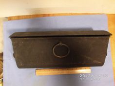 an old metal box with a ring on the front sitting on a blue piece of paper