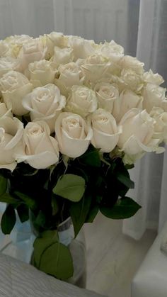 a vase filled with white roses on top of a table