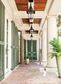 an image of a porch with green shutters and potted plant on the side