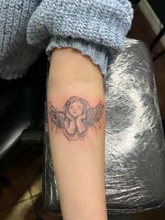 a small tattoo on the arm of a woman with an angel and baby in her arms