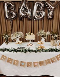 a baby shower table with balloons and desserts