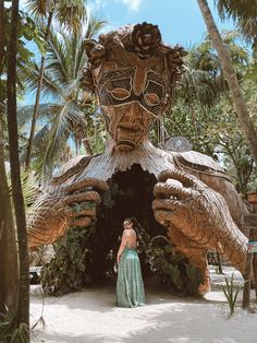 a woman standing in front of a wooden sculpture