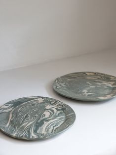 two plates sitting on top of a white counter next to each other in front of a wall