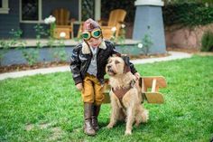 a little boy standing next to a dog wearing goggles