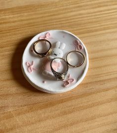 three wedding rings are placed on a plate with bunny ears and pink bows around them