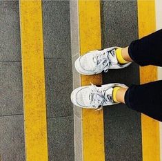 two people standing next to each other near yellow and white striped lines on the ground