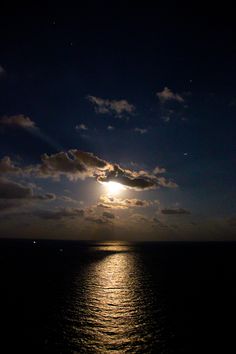 the sun is setting over the ocean with clouds in the sky and water below it