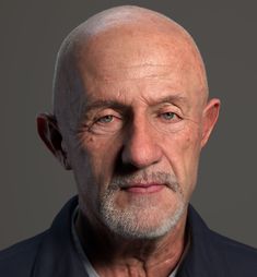 an older man with white hair wearing a black shirt and blue blazer looking at the camera