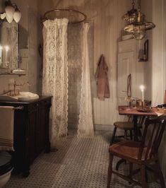 a bathroom with a sink, toilet and shower stall in the corner is lit by candles