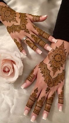 two hands with henna tattoos on them and a rose in the middle of each hand