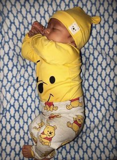 a baby in winnie the pooh outfit sleeping on a blanket