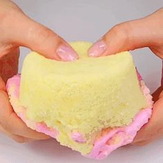 two hands holding a yellow and pink cake