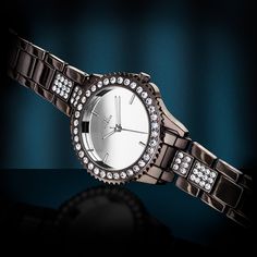 a women's watch with diamond bezels on an elegant bracelet, against a dark background