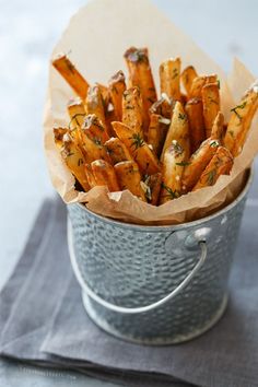 a metal bucket filled with french fries covered in herbs