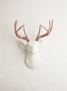 a white deer head with pink glitter antlers on it's back and side