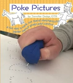 a child's hand holding a small blue object on top of a white table