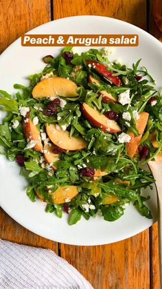 a salad with apples, cheese and cranberries is on a white plate next to a wooden table