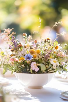 a white bowl filled with lots of flowers on top of a table