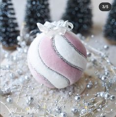 a pink and white striped ornament sitting on top of a table next to christmas trees