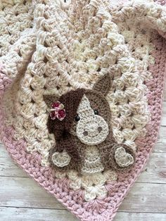 a crocheted blanket with a small stuffed animal on the front and back side