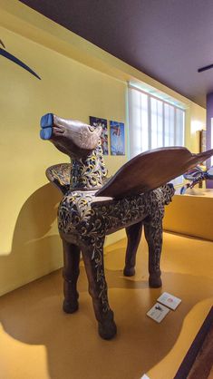 a wooden horse statue sitting on top of a yellow floor next to a blue wall