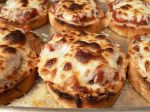 small pizzas with cheese and sauce on them sitting in a baking pan, ready to be eaten