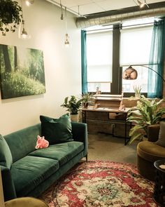 a living room with green couches and rugs in front of two large windows