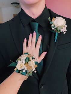 a man in a suit and tie with flowers on his lapel, wearing a ring