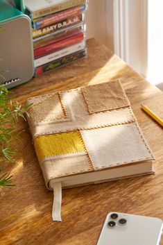 an open book sitting on top of a wooden table next to a phone and plant