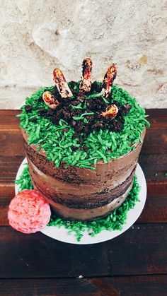 a chocolate cake with green frosting and sprinkles sitting on top of a wooden table