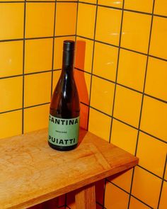 a bottle sitting on top of a wooden table in front of yellow tiled walls and floor