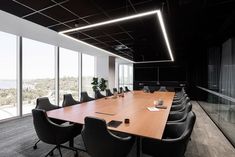 an empty conference room with black chairs and wooden table in front of large glass windows