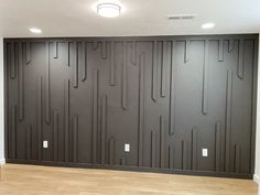 an empty room with wood flooring and black wall paneling on the back wall