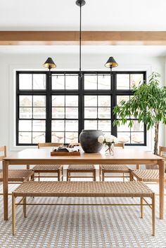 the dining room table is surrounded by two large windows