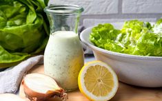 lettuce, lemon and dressing on a cutting board next to a bowl of salad