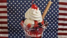 an ice cream sundae with strawberries, blueberries and cherries in a glass vase