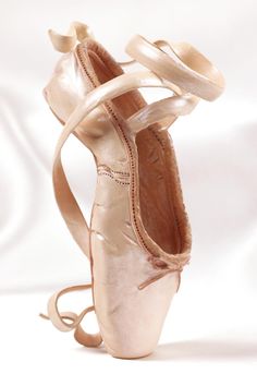 a ballerina's ballet shoe with straps tied around the bottom and heel, on a white background