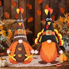 two stuffed turkeys wearing thanksgiving hats and standing next to each other on a table