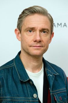 a man in a denim jacket is looking at the camera