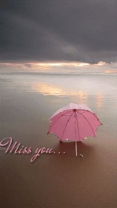 a pink umbrella sitting on top of a sandy beach next to the ocean under a cloudy sky