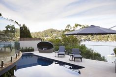 an outdoor pool with chairs and umbrellas next to it