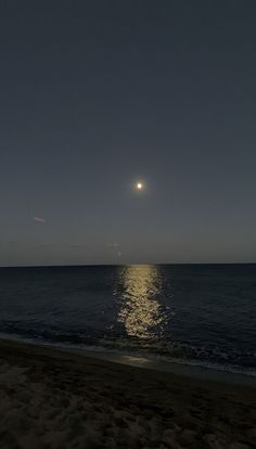 the moon is shining over the ocean on a clear night with no one in sight